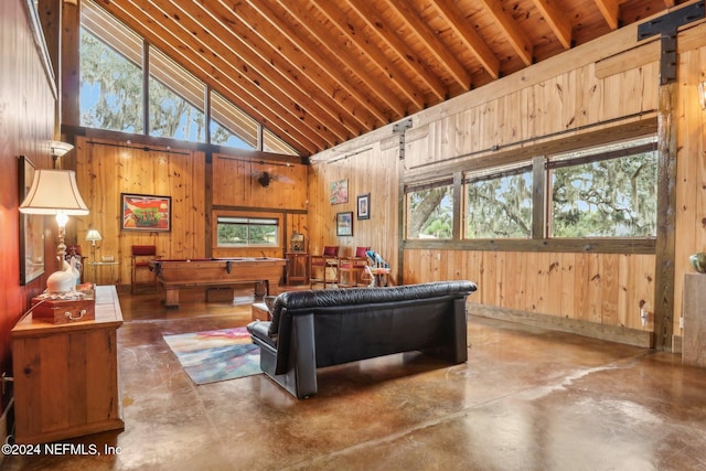 living area with wooden walls, finished concrete floors, and high vaulted ceiling