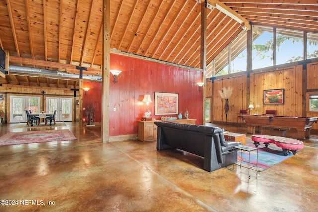 living area with concrete floors, wood walls, and high vaulted ceiling