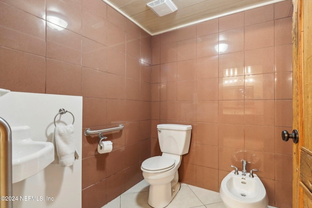 bathroom with a bidet, tile patterned floors, toilet, and tile walls