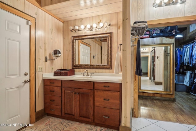 bathroom with wooden walls, vanity, and tile patterned floors