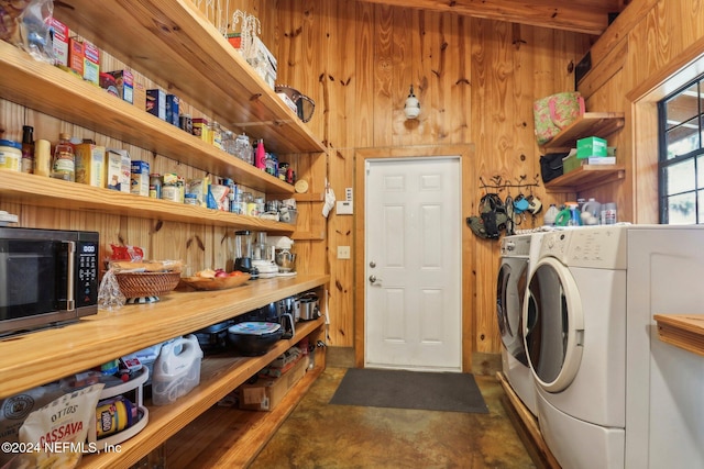 clothes washing area featuring wooden walls, laundry area, and washer and clothes dryer