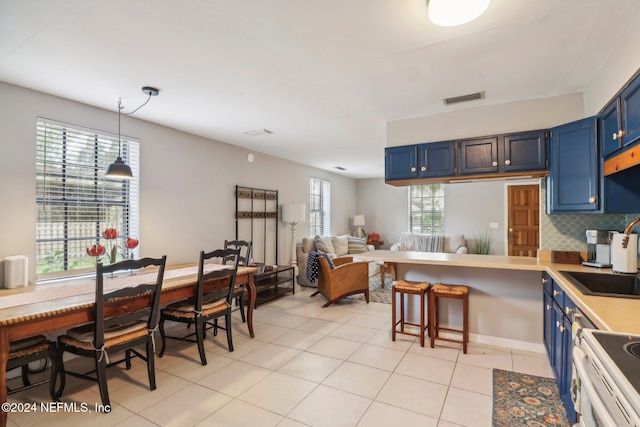 kitchen with visible vents, hanging light fixtures, blue cabinetry, backsplash, and light tile patterned flooring