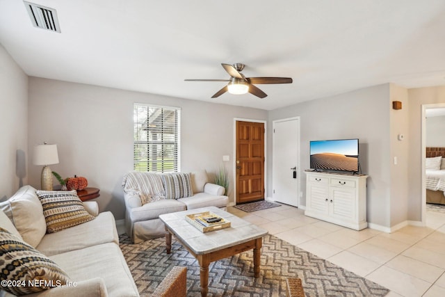 living room featuring light tile patterned floors, ceiling fan, visible vents, and baseboards