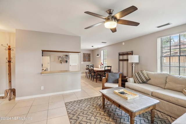 living room featuring a ceiling fan, visible vents, baseboards, and light tile patterned floors