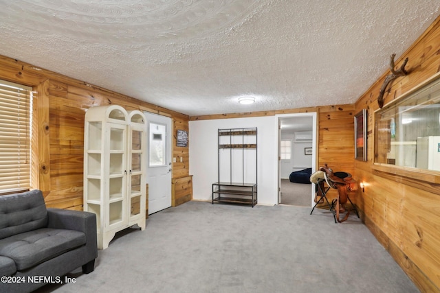 living area with a textured ceiling, carpet floors, and wood walls