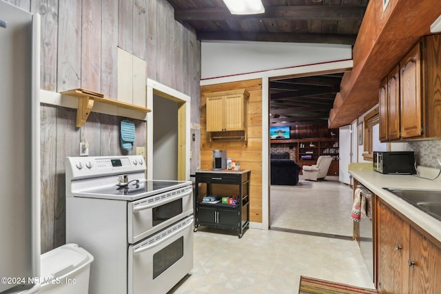 kitchen featuring light countertops, wood walls, double oven range, black microwave, and stainless steel dishwasher