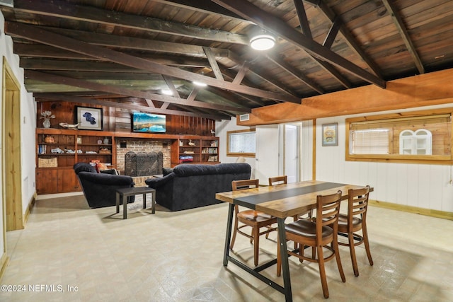 dining area featuring a fireplace, wood walls, lofted ceiling with beams, and tile patterned floors