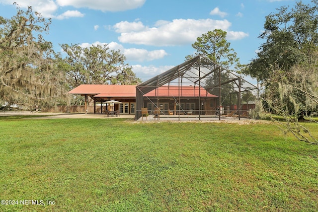 back of property featuring glass enclosure, a yard, and a patio