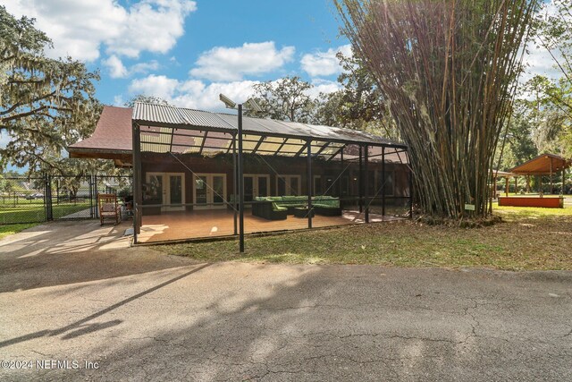 back of property with a gate, fence, french doors, and metal roof