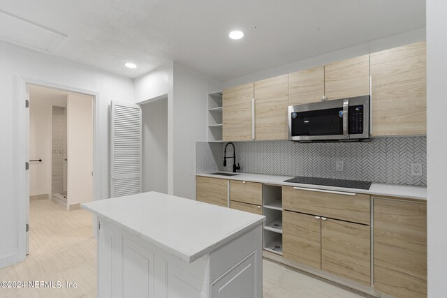 kitchen with black cooktop, a center island, decorative backsplash, and sink