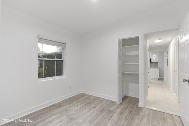 unfurnished bedroom with light wood-type flooring and a closet