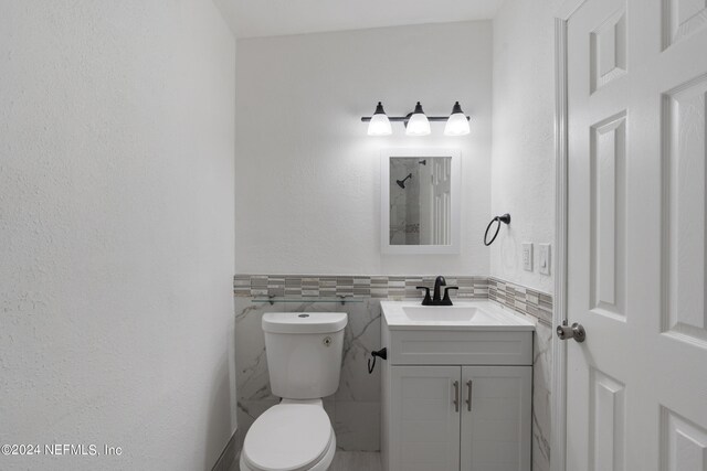 bathroom featuring vanity, toilet, tile walls, and decorative backsplash