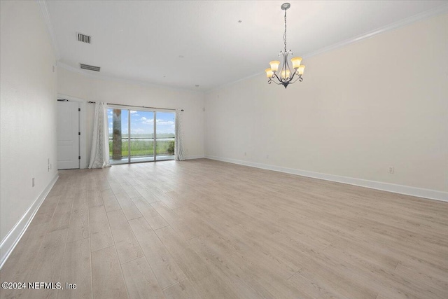 spare room featuring ornamental molding, light wood-type flooring, and a chandelier