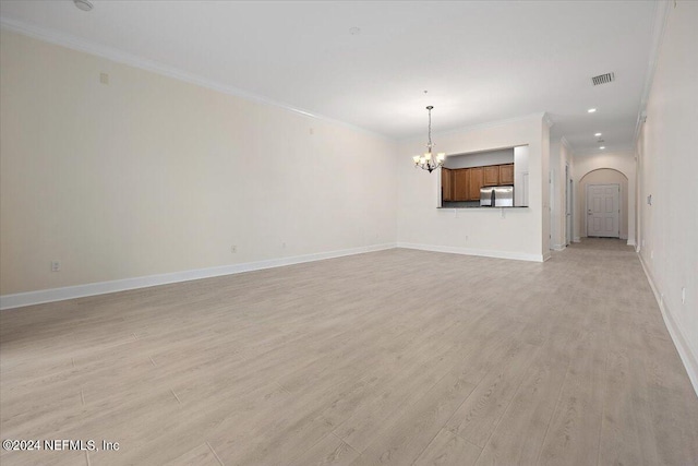 unfurnished living room featuring ornamental molding, light wood-type flooring, and a chandelier