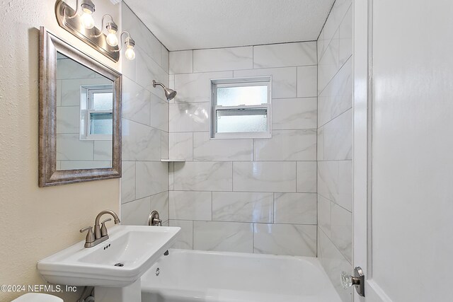 full bathroom featuring tiled shower / bath combo, a wealth of natural light, and sink