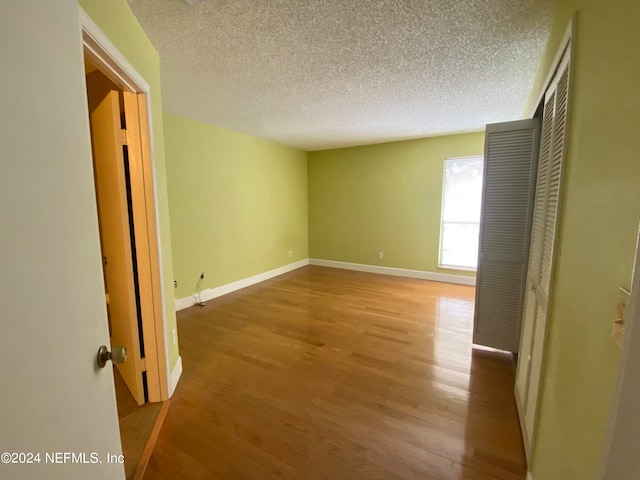 empty room featuring light wood-type flooring and a textured ceiling