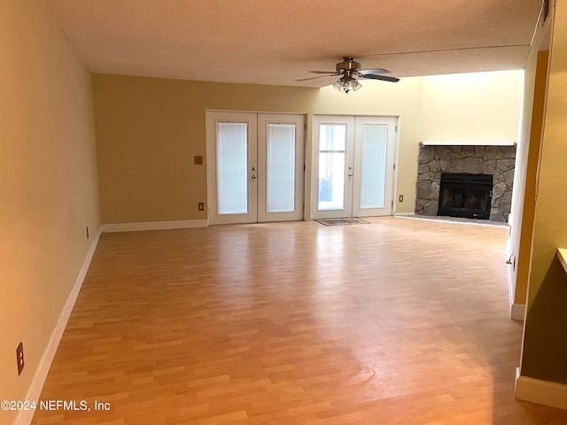 unfurnished living room with a textured ceiling, ceiling fan, french doors, and light hardwood / wood-style flooring