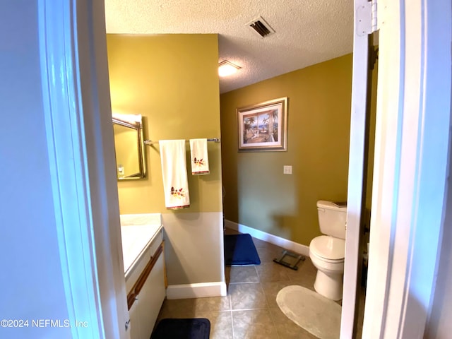 bathroom featuring vanity, tile patterned flooring, toilet, and a textured ceiling