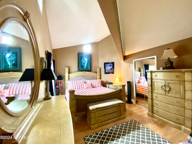 bedroom with light wood-type flooring, lofted ceiling, and a closet