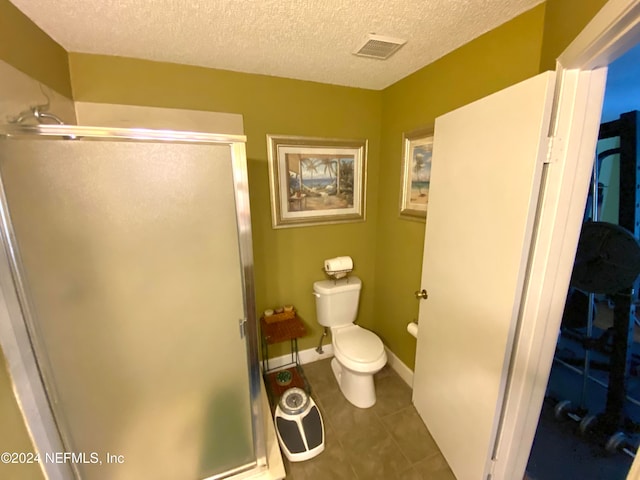 bathroom featuring tile patterned flooring, walk in shower, a textured ceiling, and toilet