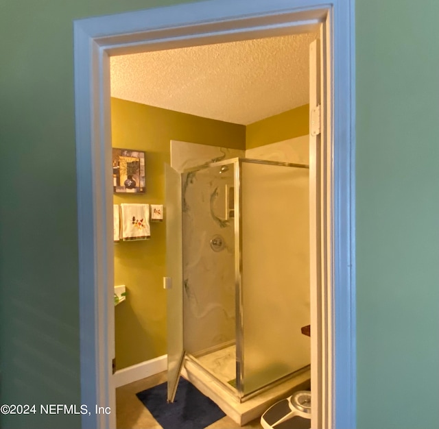 bathroom with walk in shower and a textured ceiling