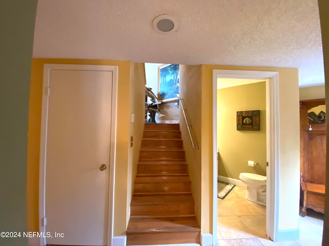 stairs with tile patterned floors and a textured ceiling