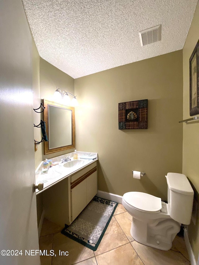 bathroom with a textured ceiling, tile patterned flooring, vanity, and toilet