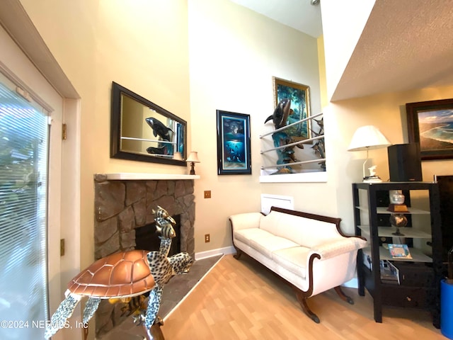 sitting room featuring a stone fireplace, a textured ceiling, and hardwood / wood-style floors