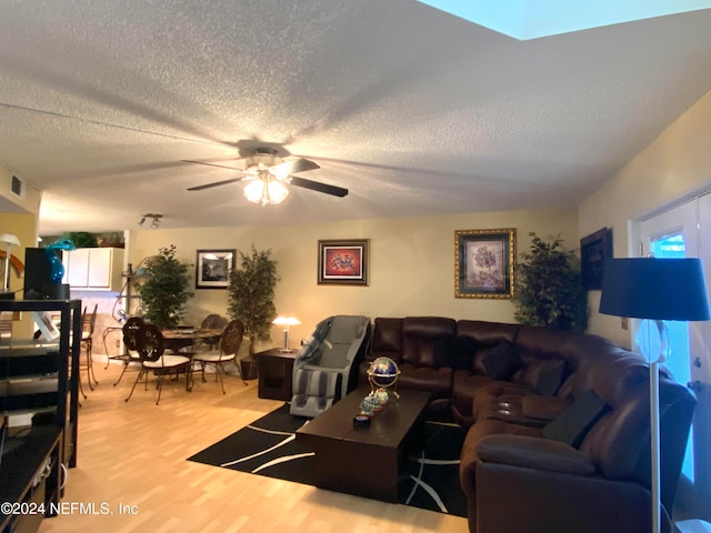 living room with hardwood / wood-style flooring, ceiling fan, and a textured ceiling