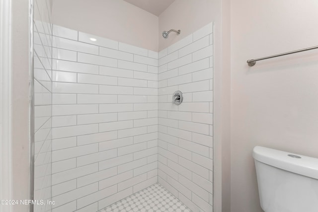 bathroom featuring tiled shower and toilet