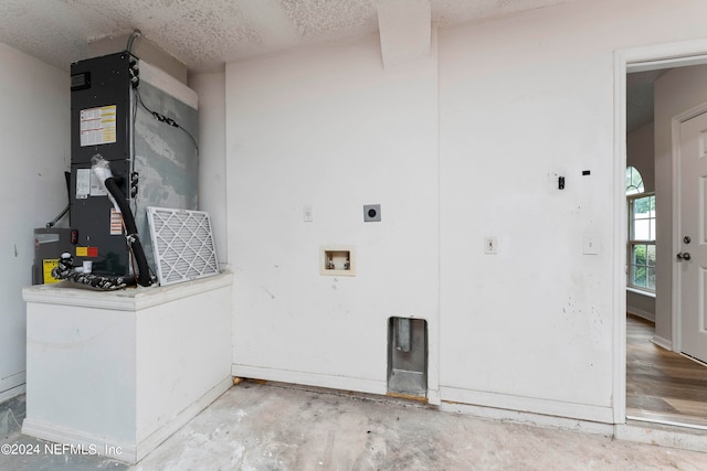 washroom with heating unit, hookup for a washing machine, a textured ceiling, and electric dryer hookup