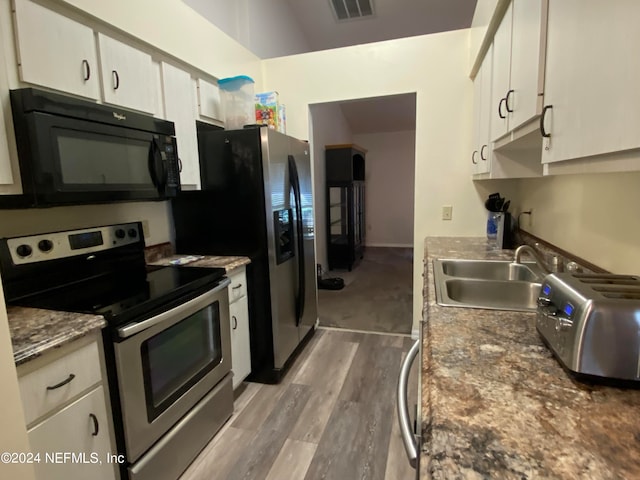 kitchen featuring stainless steel range with electric stovetop, white cabinetry, hardwood / wood-style floors, and sink