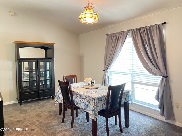 carpeted dining space with lofted ceiling