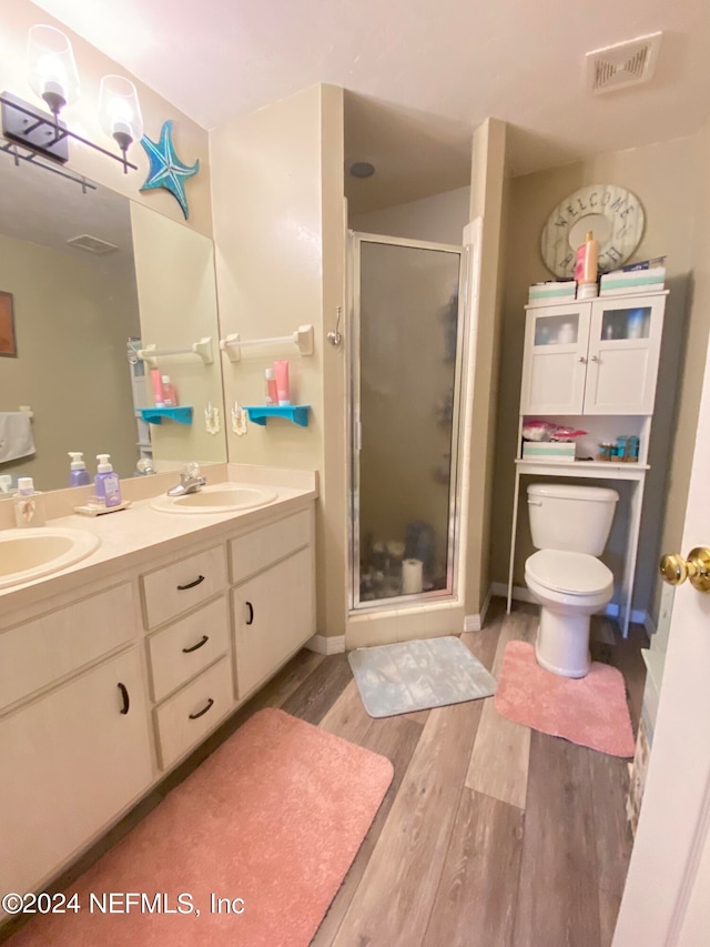 bathroom featuring vanity, toilet, walk in shower, and hardwood / wood-style floors