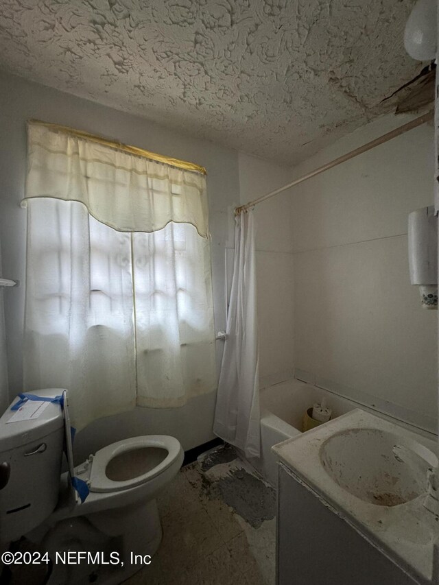 full bathroom featuring vanity, toilet, a textured ceiling, and shower / bath combo