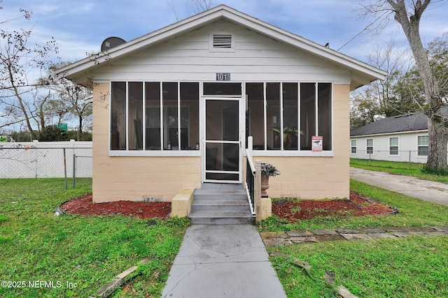 bungalow-style house with a sunroom and a front yard