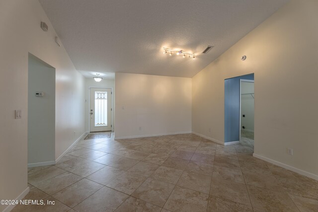 spare room featuring lofted ceiling and a textured ceiling