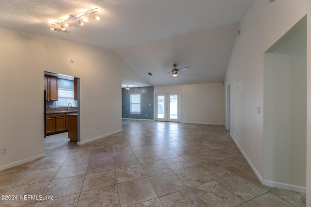 spare room featuring a textured ceiling, french doors, sink, lofted ceiling, and ceiling fan