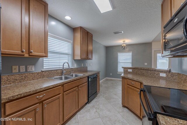 kitchen with a textured ceiling, black appliances, sink, and light tile patterned floors