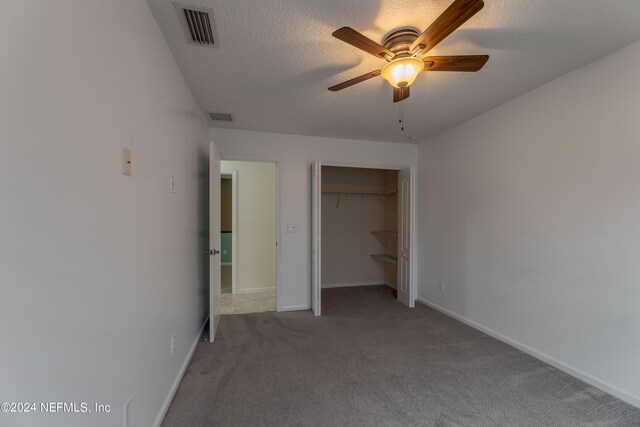 unfurnished bedroom with a closet, a textured ceiling, ceiling fan, and carpet flooring