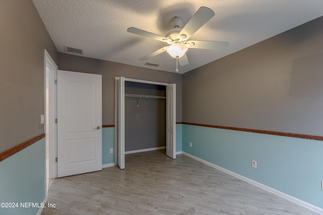 unfurnished bedroom featuring light wood-type flooring, a closet, ceiling fan, and a textured ceiling