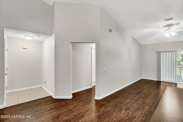 unfurnished room with lofted ceiling, ceiling fan, dark hardwood / wood-style flooring, and a textured ceiling