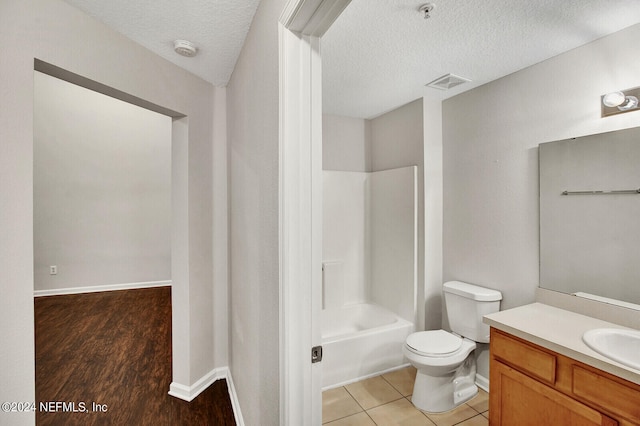 full bathroom with toilet, vanity, a textured ceiling, shower / bathing tub combination, and wood-type flooring