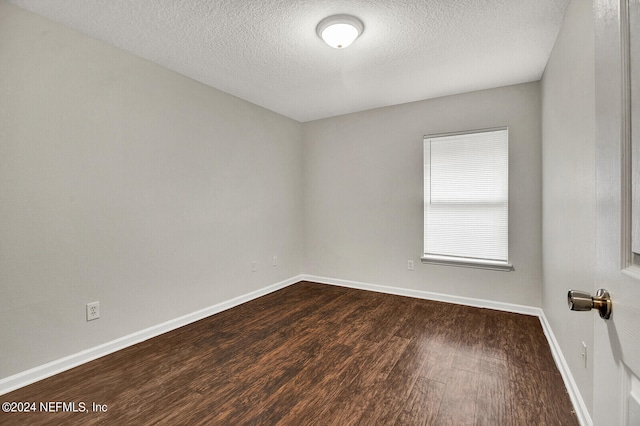 empty room featuring a textured ceiling and dark hardwood / wood-style floors