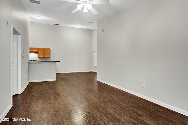 unfurnished living room featuring dark wood-type flooring and ceiling fan