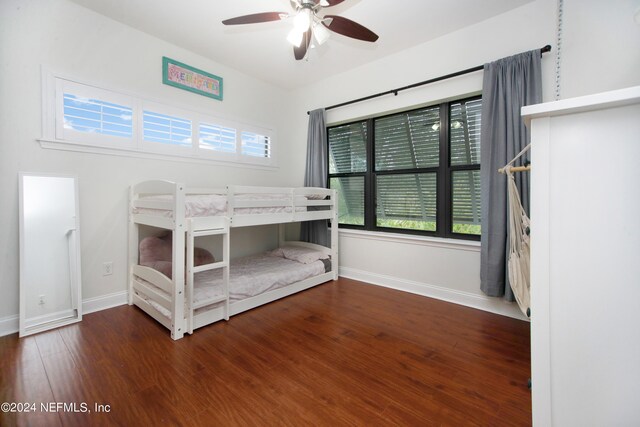 unfurnished bedroom featuring multiple windows, ceiling fan, and dark wood-type flooring