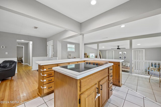 kitchen featuring ceiling fan, kitchen peninsula, a kitchen island, light hardwood / wood-style flooring, and black electric stovetop