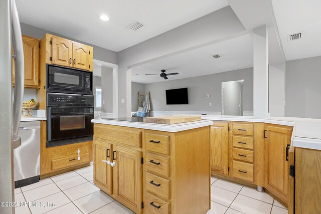 kitchen with black appliances, light tile patterned floors, a kitchen island, and ceiling fan