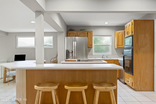 kitchen with a kitchen island, a kitchen breakfast bar, sink, and black appliances