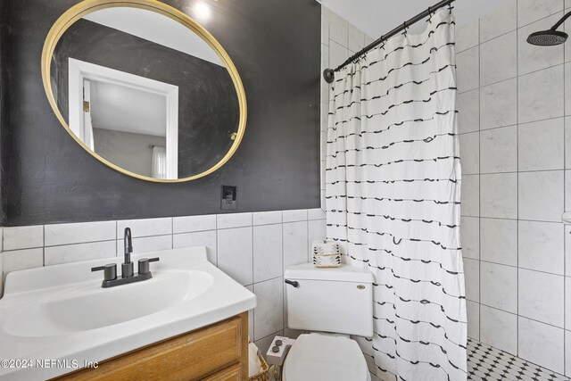 bathroom featuring walk in shower, vanity, tile walls, and toilet